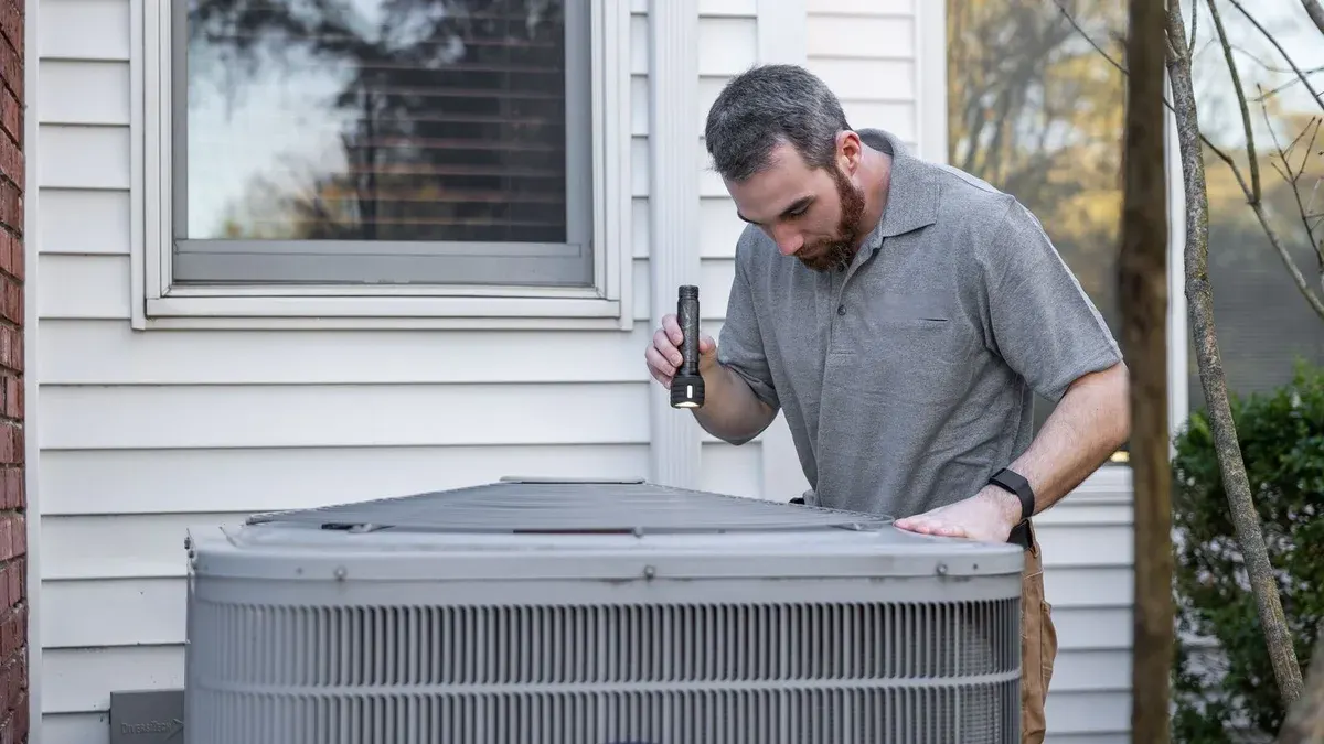 HVAC technician inspecting a residential outdoor air conditioning unit